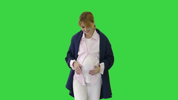 Happy and Proud Pregnant Woman Looking at Her Belly While Walking on a Green Screen, Chroma Key.