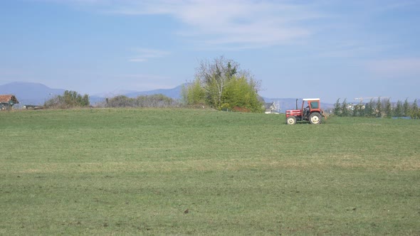 Tractor working on cultivated fields farmland on the mountains, agriculture occupation, lush green c