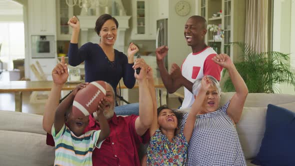 Three generation family cheering while watching TV at home