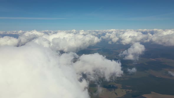 Aerial View From Airplane Window at High Altitude of Earth Covered with White Puffy Cumulus Clouds