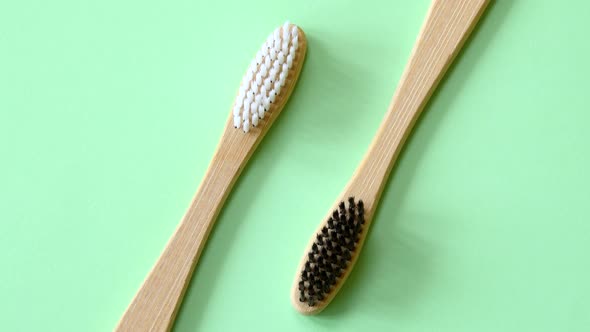 Bamboo toothbrushes rotating on light green background