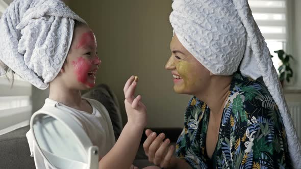 Little Girl with a Cosmetic Mask on Her Face Helps Her Mother To Make a Cosmetic Mask