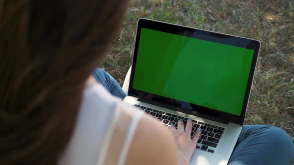 Woman Working on the Laptop Computer with Green Screen at Park. Chroma Key. View From the Back