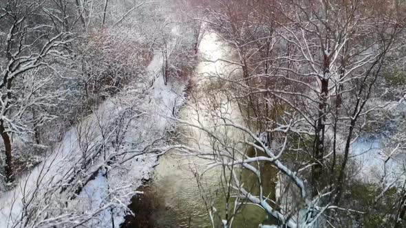Rising drone shot over wintry forest and creek in Michigan, USA