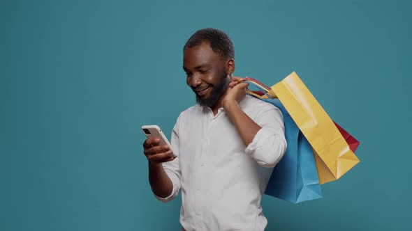 Modern Person Carrying Shopping Bags and Using Smartphone