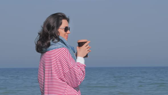 Young Woman Drinking Hot Beverage on Beach