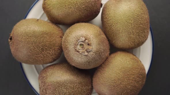 Bunch of fresh kiwi in a white plate with a blue border. Brown hairy peel. 