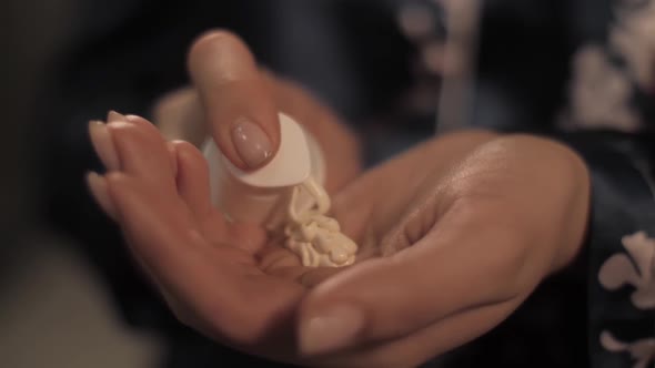 Beautiful Girl in Front of the Mirror Applies Moisturizer on Her Hand