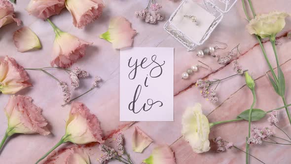 YES I DO card on a marble table near pink flowers top view zoom in