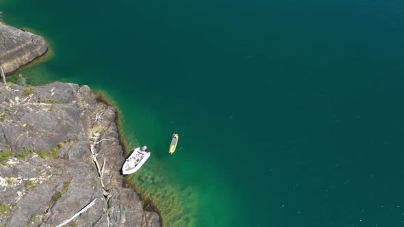 Aerial top down of a man in a kayak near a rocky shore in turquoise water Puelo Lake, Patagonia Arge