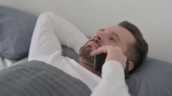 Man Talking on Call on Smartphone While Laying in Bed