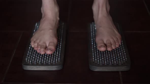 Female bare feet stand on wooden sadhu board with sharp nails. Yoga practice. Auserity. Close up 4K