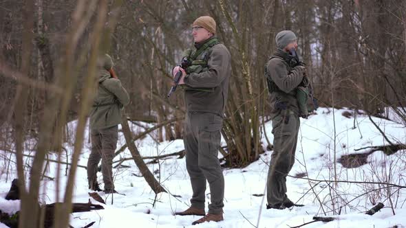 Cautious Brave Men and Woman Standing in Winter Forest with Guns Looking Around