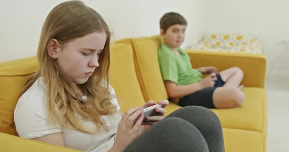 Two Kids with Gadgets. Sister and Brother Surfing the Net or Playing Online Games on Smartphone and