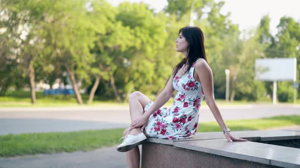 Round Motion Long Haired Brunette Girl Sits on Grey Parapet