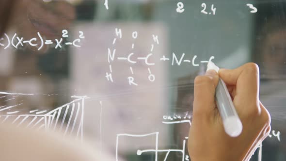 Young Attractive Female Office Worker Writing on Glass Whiteboard Close Up