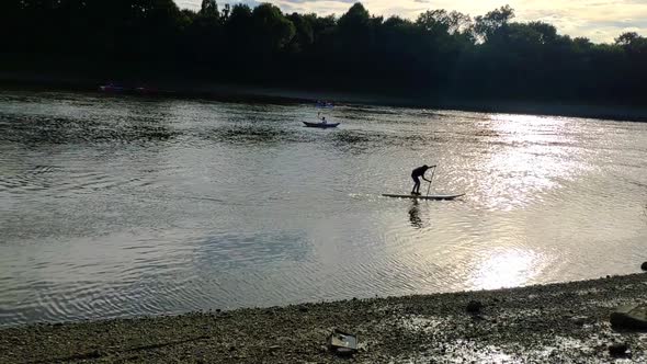 A kid is seen paddling on a Stand Up Paddle board on river Thames in London on a sunny summer day. S