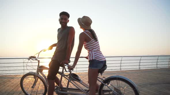 Portrait of a Mixed Race Couple Riding on Tandem Bicycle Outdoors Near the Sea Slow Motion