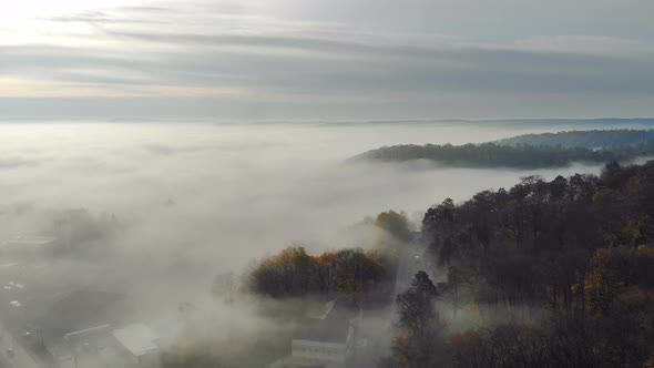 Flying Over the Fabulous Morning Mist Over the City. The Sunrise and the Colored Rays Reflected in