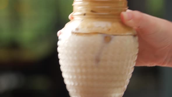 Female Hand Putting Down a Homemade Dalgona Coffee in a Mason Jar