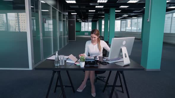 Working Overtime Young Businesswoman Sits at a Desk in the Office and Works on a Pc Manager Works on