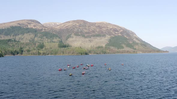 Aerial View of Canoeists in a Lake Surrounded by Mountains and Nature