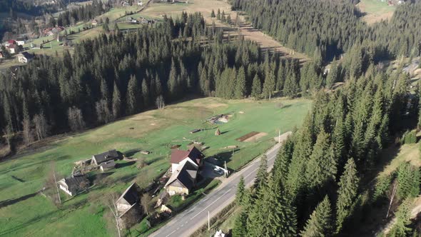 Cottages in mountains, aerial drone view. Mountains with pine trees forest.