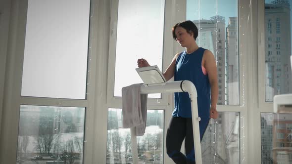 Attractive fit female is training on treadmill, touching screen, using new technology