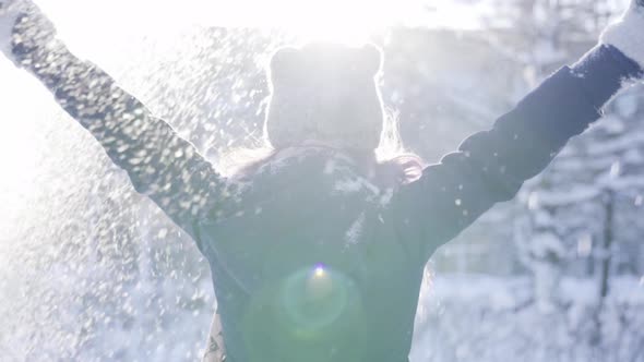 Happy Young Woman Throwing Up the Snow Up