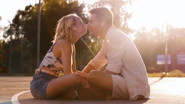 Happy Couple with Smartphone and Earphones in City