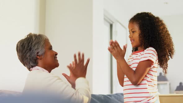 Granddaughter and grandmother playing clapping games in living room 4k