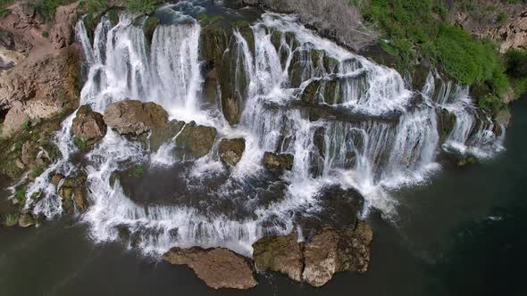 Flying view of waterfall flowing over edge into river