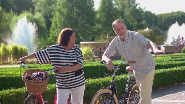 Cheerful Senior Couple with Bicycles at Summer Park