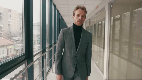 Handsome confident successful adult businessman in formal clothes walking indoor modern office build