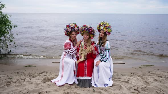 Wide Shot Portrait of Beautiful Ukrainian Women Sitting on River Shore Looking at Camera Smiling