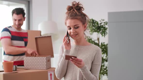 Smiling woman using phone while moving house 