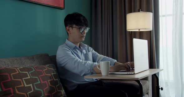 Attractive Asian Vietnam Man Busy Work Computer or Smart Tablet on Laptop at Home in Freelance Data