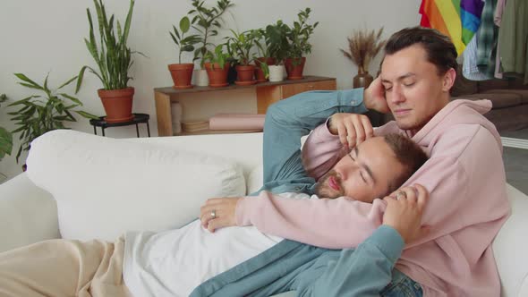 Two Lgbt Men are Lying on the Sofa Looking at Each Other and Stroking Hair