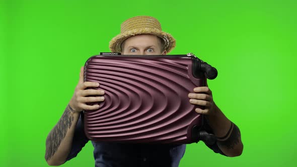 Portrait of Man Tourist Hides Behind a Suitcase and Looks Out, Chroma Key
