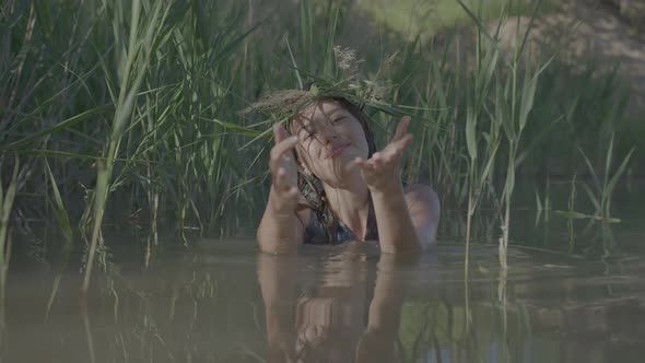 Beautiful Water Maiden with a Wreath on Her Head Smiling Comes Out of the Water