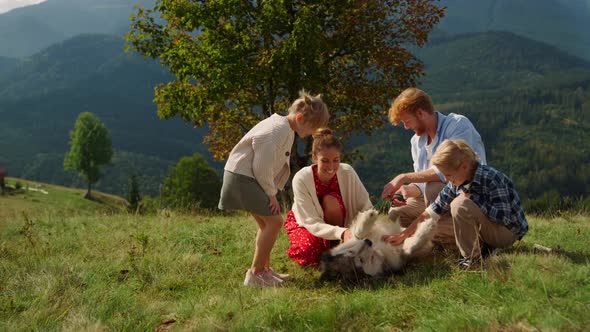 Happy Family Caressing Dog on Mountains Hill