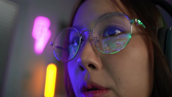 Focus eyes glasses of asian woman playing online computer video game with lighting effect.
