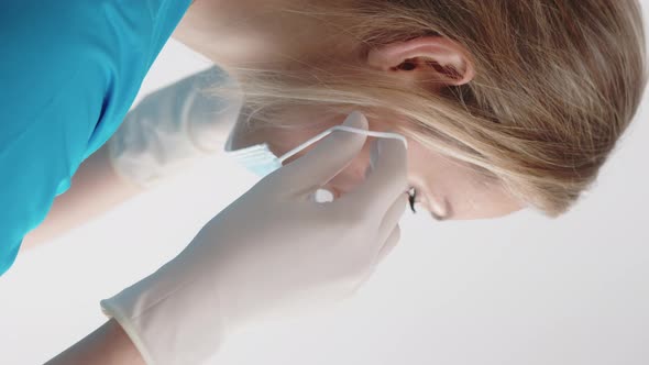 Vertical Closeup Portrait of a Young Caucasian Blond Female Doctor in Protective Gloves and