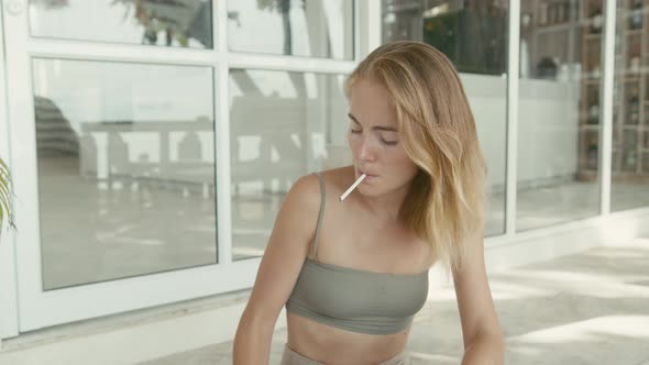 Pretty Young Woman with Vitiligo Pigmentation Sits on the Stairs and Smokes