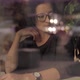 Young Attractive Girl in Glasses Sitting a Coffee Shop. View Through Window. People Passing By. - VideoHive Item for Sale
