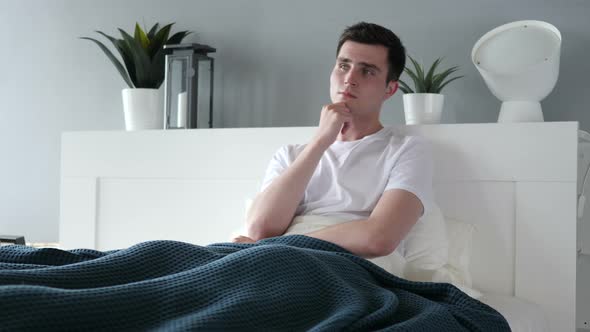 Pensive Man Thinking while Sitting in Bed