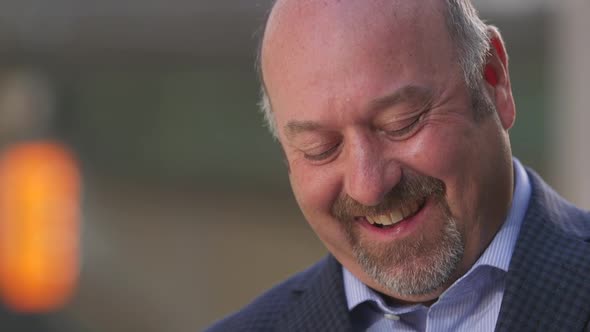 Close up of man reading text message and smiling and laughing