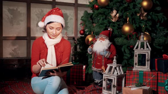 Cute Woman in Front of Christmas Tree Reading Book