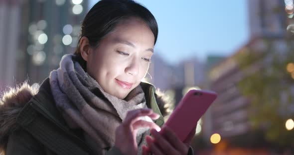 Woman use of mobile phone in city at night