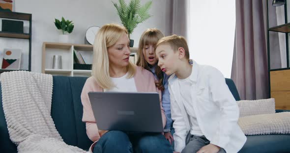 Mother Revisioning Interesting Video on Laptop Together with Her Smiling Friendly Son and Daughter